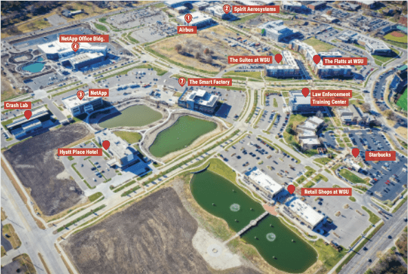 Aerial view of Wichita State University Innovation Campus showing labeled buildings, ponds, parking lots, roads, and landmarks including offices, hotels, retail shops, restaurants, and training centers.